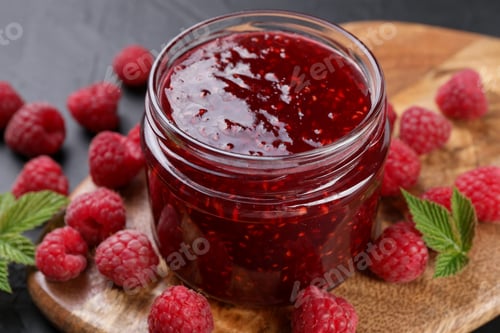 Preview: Sweet raspberry jam in glass jar and berries on gray table, closeup