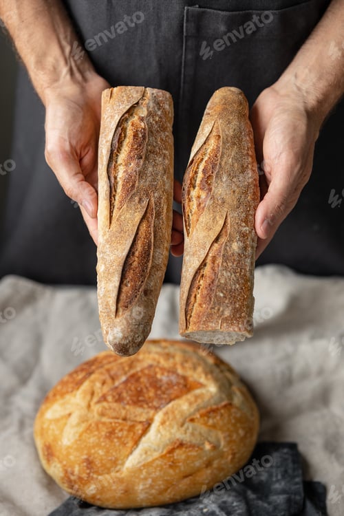 Preview: chef in a restaurant or bakery holding a sliced baguette and large round bread