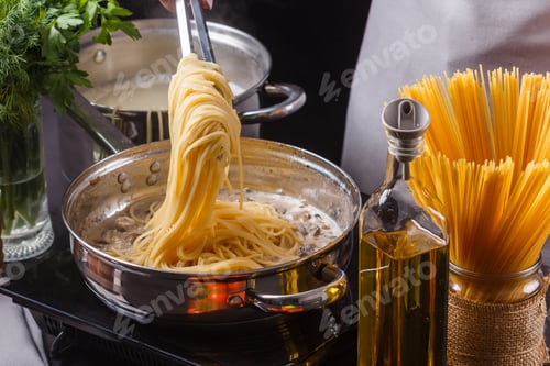 Preview: young woman in a gray apron preparing pasta