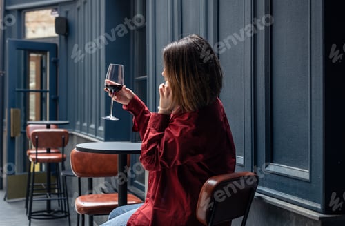 Preview: A young woman with a glass of wine on the terrace of a restaurant.