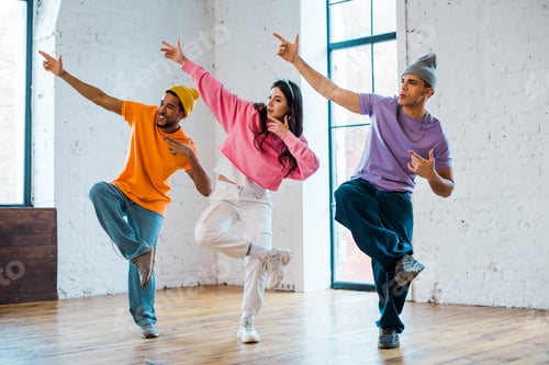 Preview: stylish woman and multicultural men gesturing and breakdancing