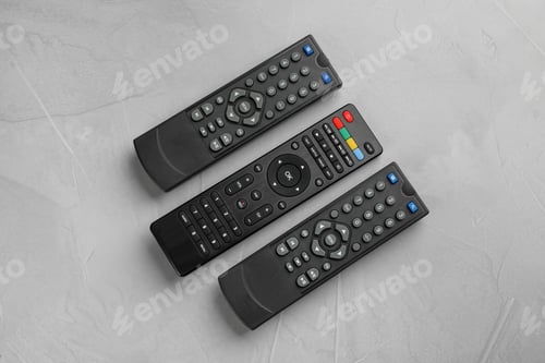 Preview: Modern tv remote controls on grey table, flat lay