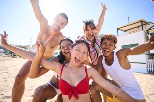 Preview: Funny portrait of excited cheerful group of young diverse friends on beach looking camera