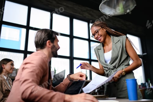 Preview: Portrait of young businesspeople working indoors in office, talking