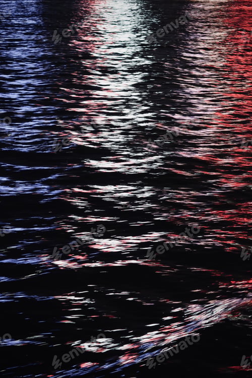 Preview: City lights reflecting on the calm sea surface at night