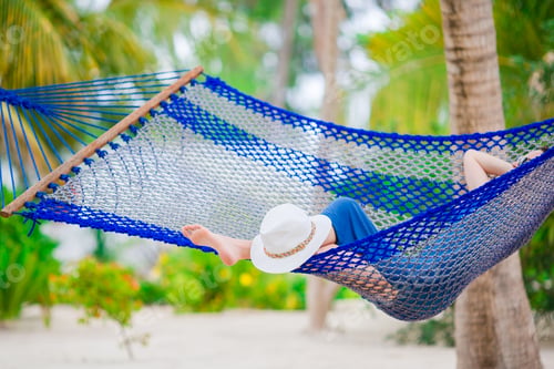 Preview: Closeup straw beach hat near relaxing young woman in hammock