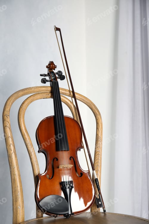 Preview: Classic violin and bow on chair near light wall