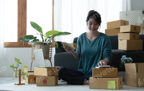 Preview: Asian women write note of orders of goods with a smiling face in concept of sme, e-commerce business