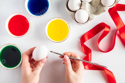 Preview: Young woman paints white eggs for easter.