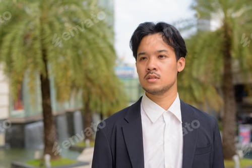 Preview: Portrait of Asian businessman outdoors in the city thinking