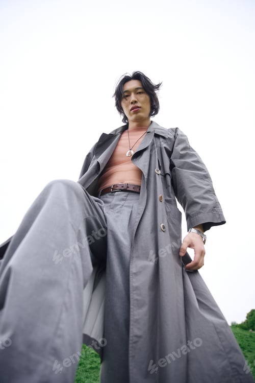 Preview: Stylish young man showcases grey outfit in a serene park setting