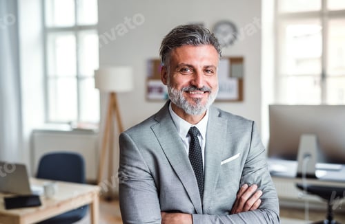 Preview: Mature businessman standing in an office, arms crossed.