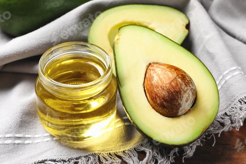 Preview: Jar with oil and ripe fresh avocado on table, closeup