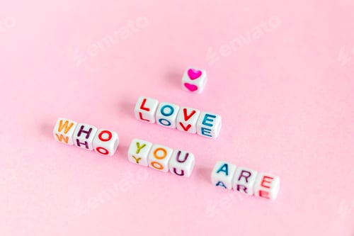 Preview: Quote "Love who you are" made out of beads on pastel pink background
