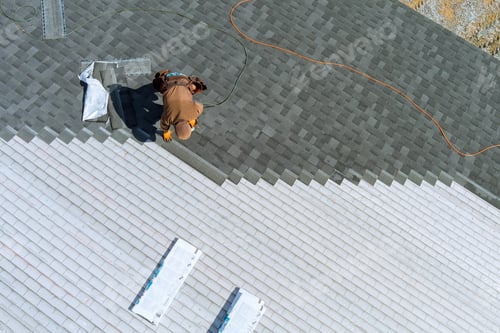 Preview: A worker installing shingles on the roof of a home