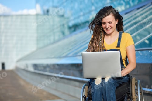 Preview: happy cute businesswoman in wheelchair working using a laptop