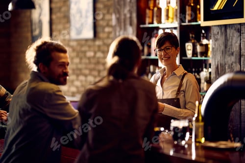 Preview: Happy waitress talking to a couple while working at bar counter.