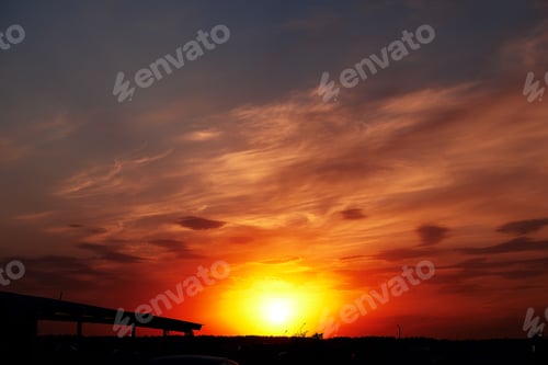Preview: Beautiful colorful dramatic sky with clouds at sunset. Bright orange setting sun low on the horizon