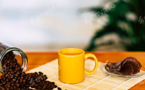 Preview: Coffee in yellow ceramic cup and coffee beans on the wooden table - chocolate biscuits on background