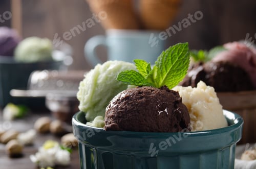 Preview: Three scoops of Vanilla pistachio and chocolate icecream balls in clay bowls on wooden kitchen table