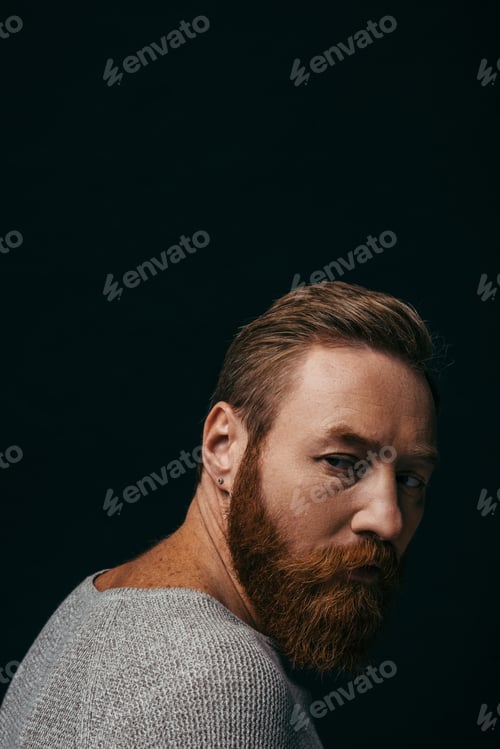 Preview: Stylish model in grey jumper looking away isolated on black