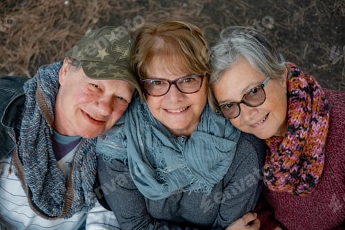 Preview: Close up view of group of smiling friends or family sitting in outdoors at wooden table