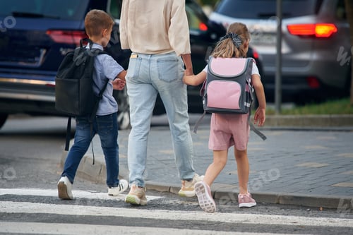 Preview: Rear view, holding hands. Woman with two kids are going to school, conception of education
