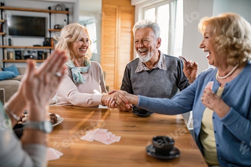 Preview: Happy mature women congratulating each other after playing cards at home.
