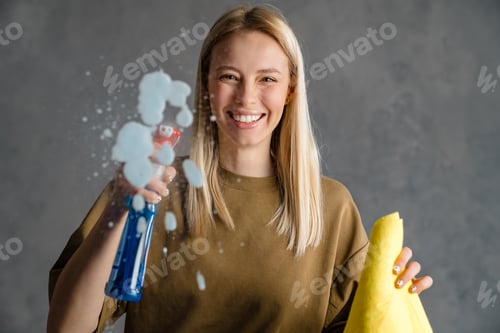 Preview: Happy blonde woman maid holding bottle of detergent
