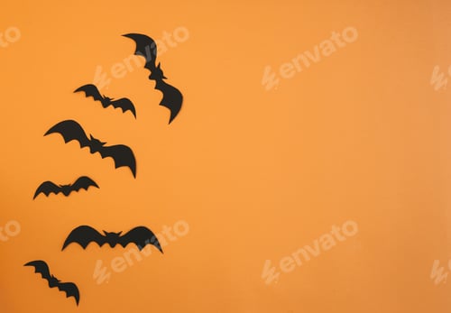 Preview: Paper bats flying on orange background. Halloween decoration concept