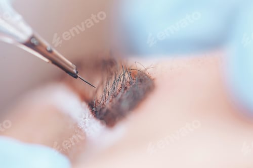 Preview: beautician making a permanent make-up procedure on eyebrows using a machine, macro photo of needle
