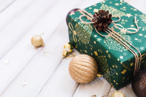 Preview: Christmas gift box with ribbon bow and ball toy on white wooden background