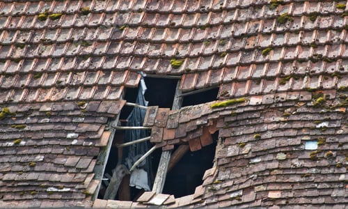 Preview: Damaged window frame in a section of a tiled roof with severe destruction