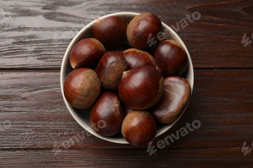 Preview: Sweet fresh edible chestnuts in bowl on wooden table, top view