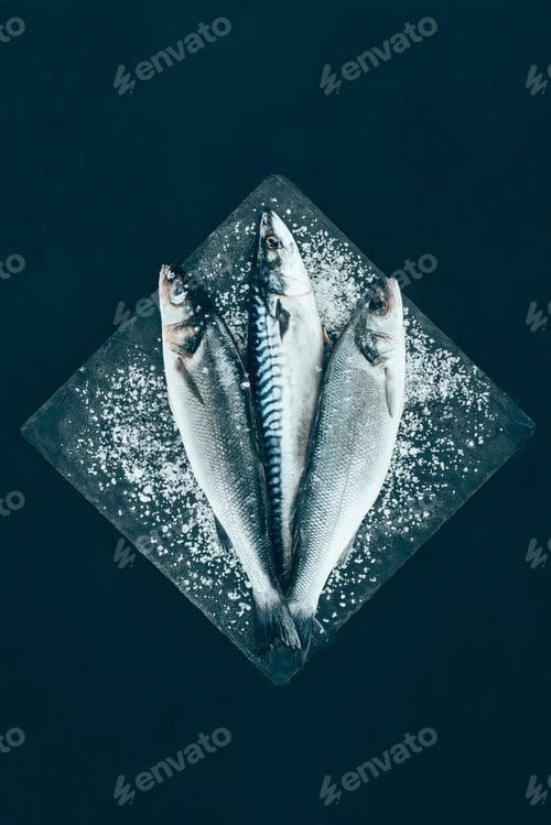 Preview: top view of fresh raw mackerel and sea bass on slate board isolated on black