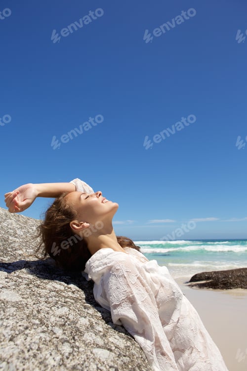 Preview: Smiling fashion model looking up at the beach