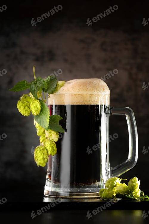 Preview: Glass of dark beer with hops around on a dark background