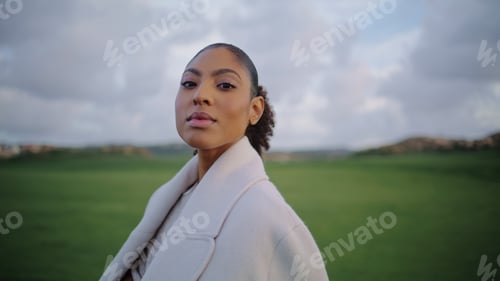 Preview: Portrait serene african american woman looking camera at green meadow view.