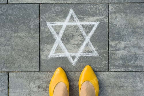 Preview: Female feet with abstract image of a six-pointed star, written on grey sidewalk.