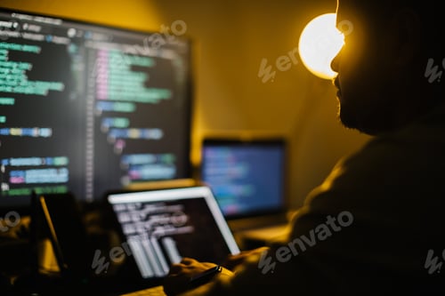 Preview: Man working at night with multiple screens