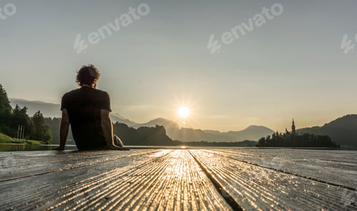 Preview: Man on the pier observing the sunrise at lake Bled.