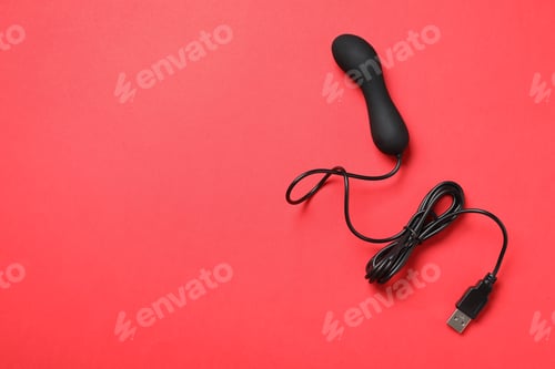 Preview: Black electric powered vibrator on red background, top view with space for text. Sex toy