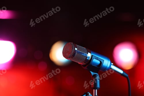 Preview: Microphone on stand against red background with blurred lights, space for text. Bokeh effect