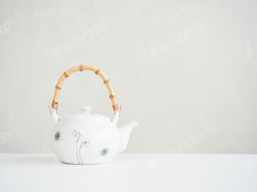 Preview: oriental style teapot decorated with carved flowers and bamboo handle on the table with copy space.x