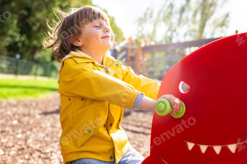 Preview: Preschool boy on children playground, happy emotional child swinging on teeterboard in a park.