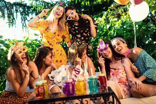 Preview: Cheerful female friends laughing and having fun making flower bouquet for new bride.
