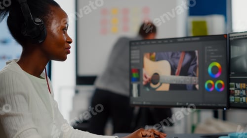 Preview: African video editor with headset listening music wihile editing footage
