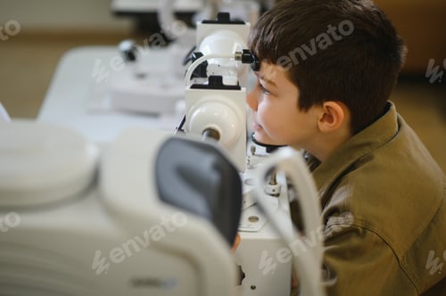 Preview: Boy undergoing eyesight examination with ophthalmologic equipment in clinic