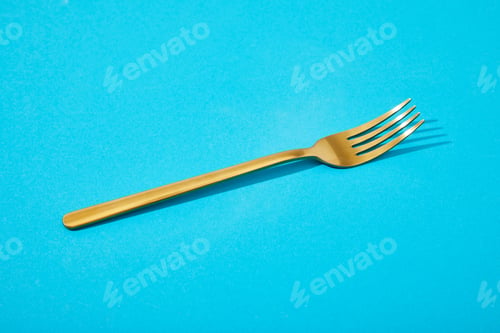 Preview: metal shiny golden fork on blue background