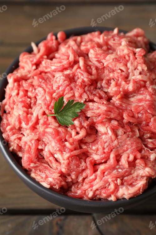Preview: Raw ground meat and parsley in bowl on wooden table, closeup